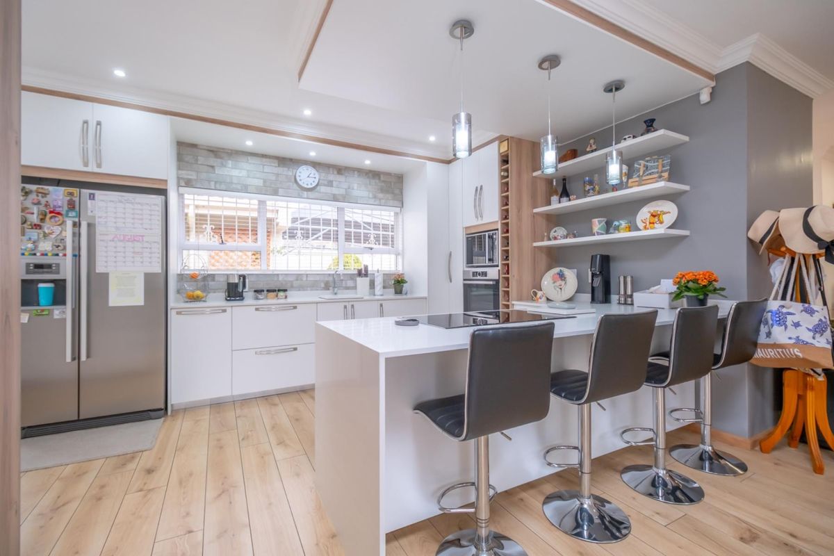 Modern kitchen featuring a central island with breakfast bar, built-in oven, microwave, and sleek cabinetry with integrated shelving and recessed lighting.