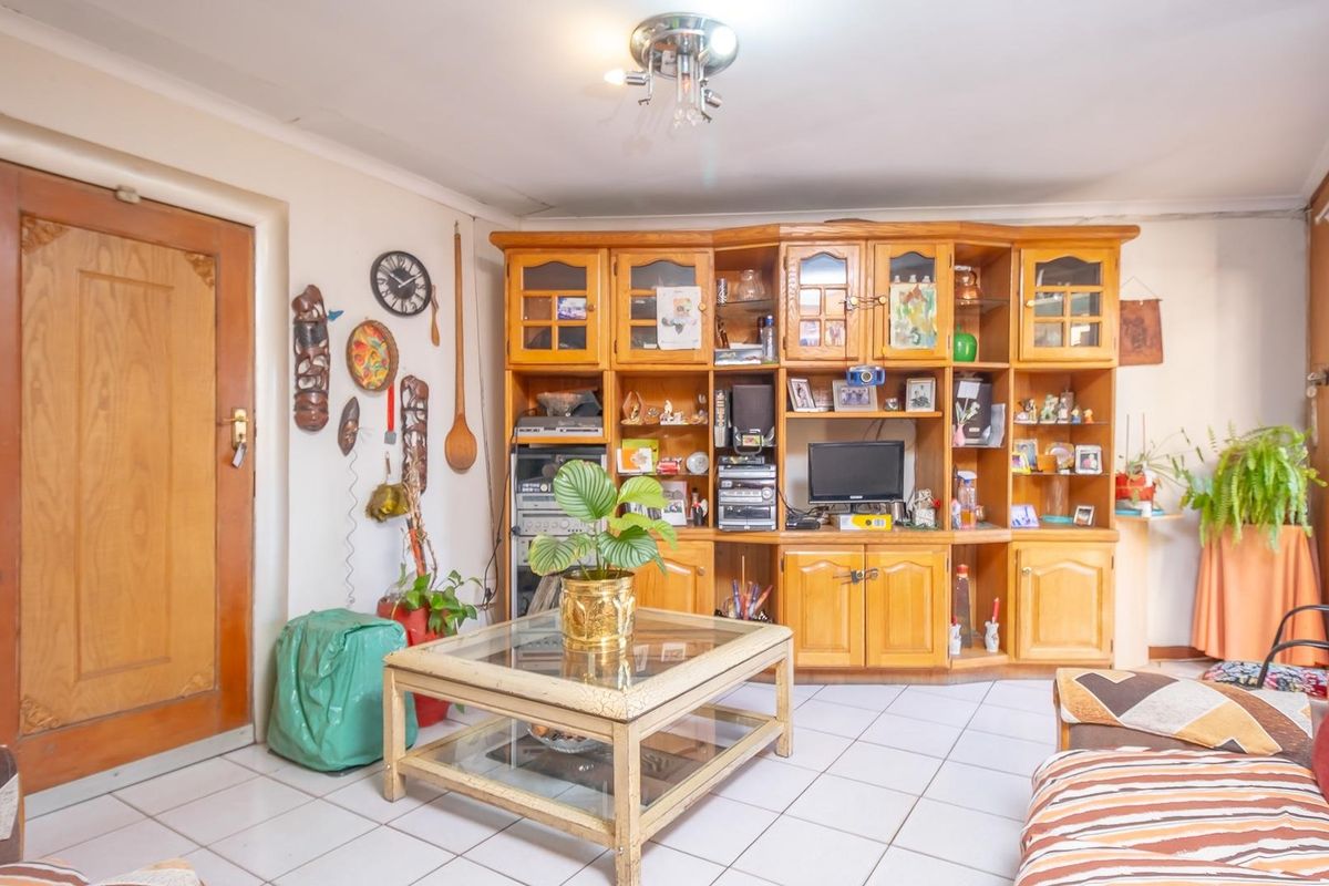 A living room featuring tiled flooring and a large built-in wooden wall unit providing ample storage and display space.