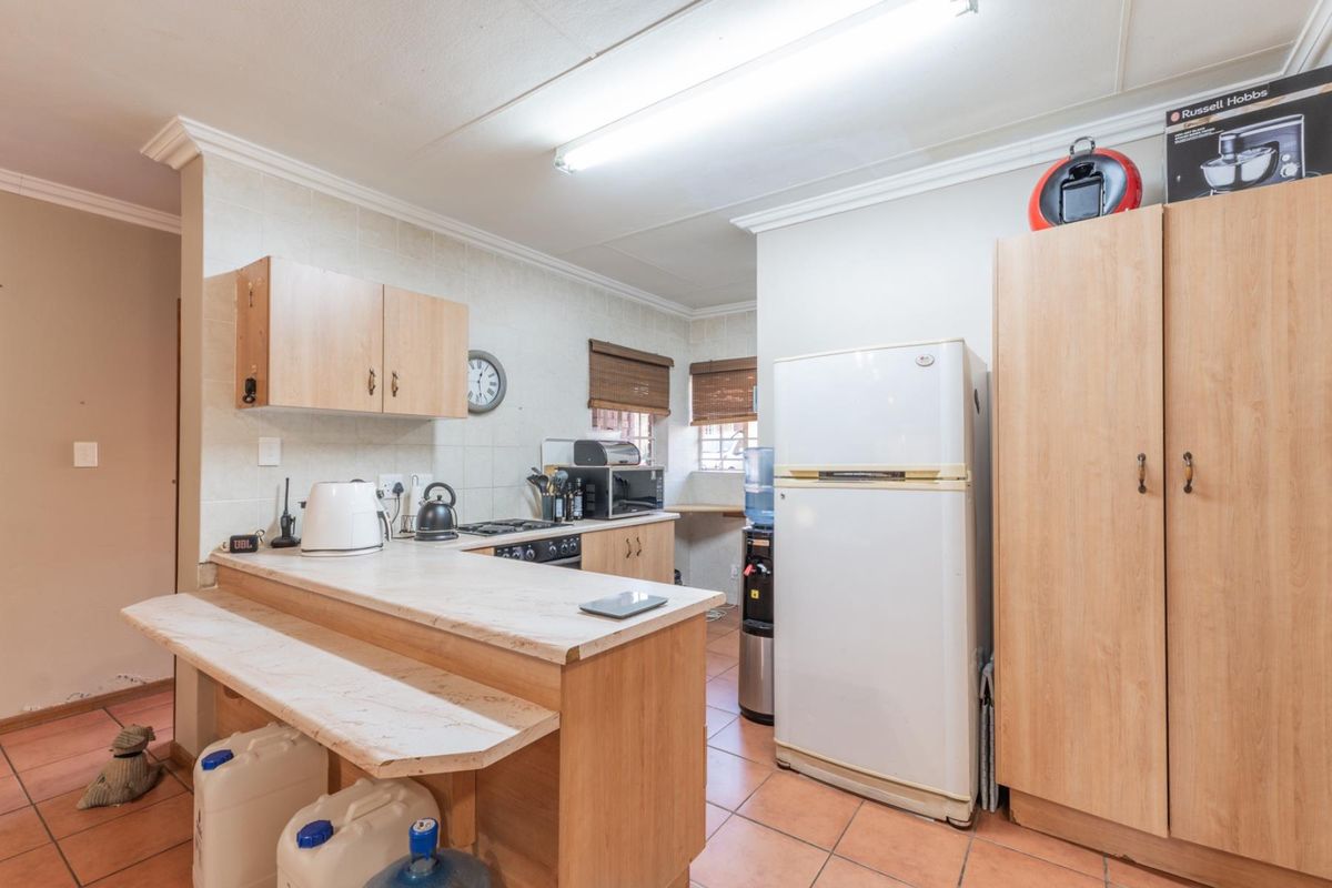 A functional kitchen featuring light wood cabinetry, a breakfast bar, tiled flooring, and built-in stove and oven.