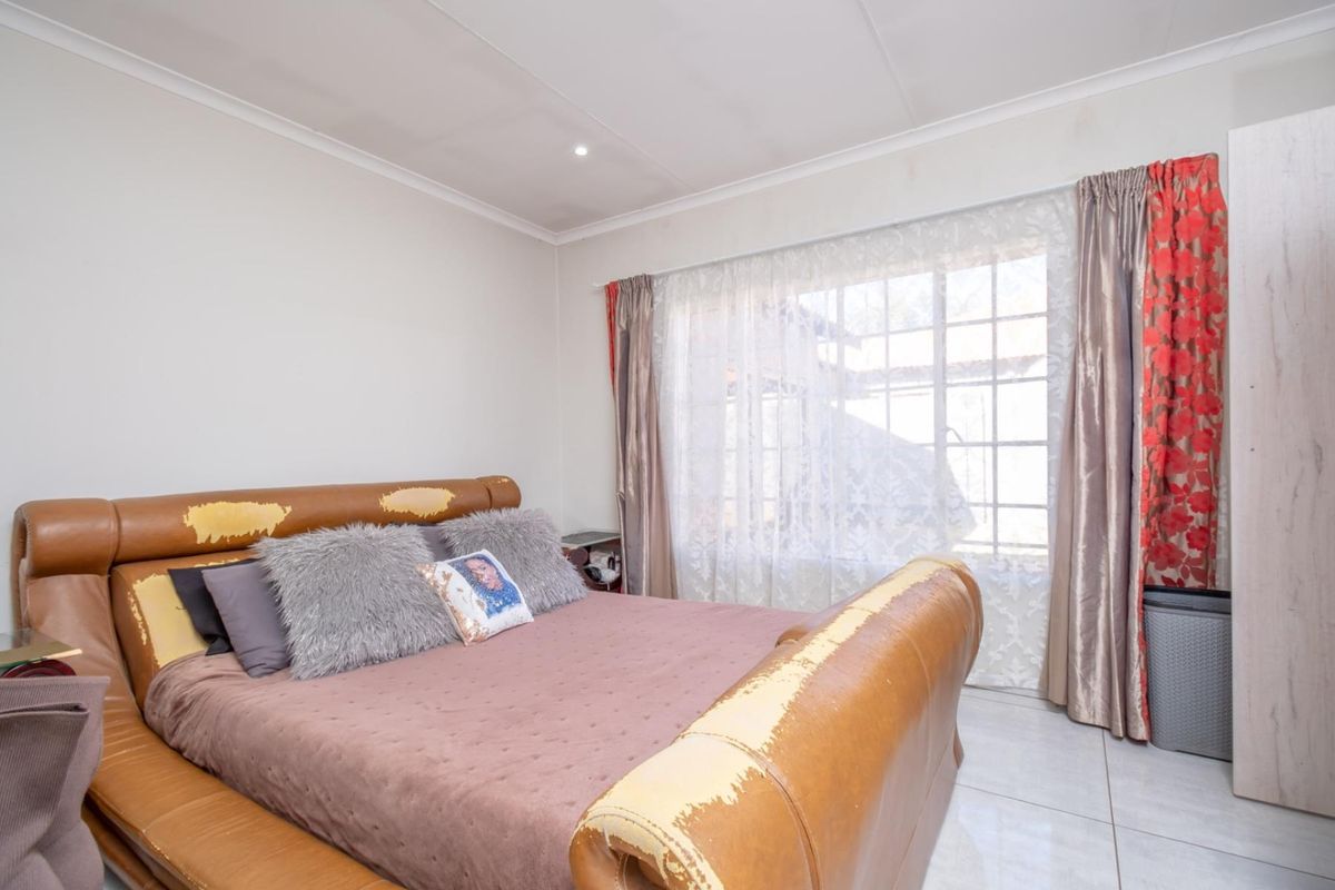 A bedroom featuring tiled flooring, a large window with curtains, and recessed ceiling lighting.
