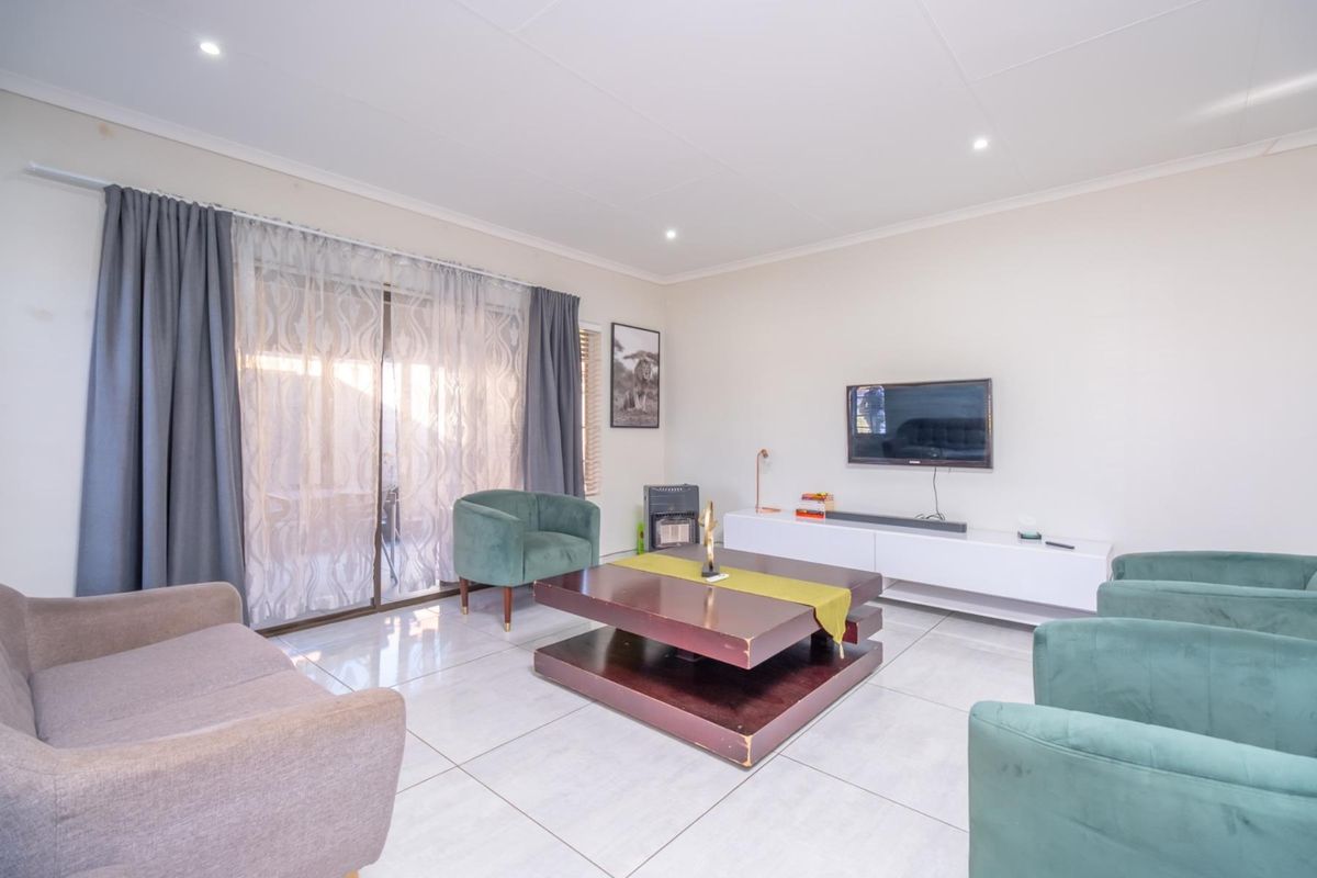 A bright and spacious living room featuring large sliding glass doors, tiled flooring, and recessed ceiling lighting.