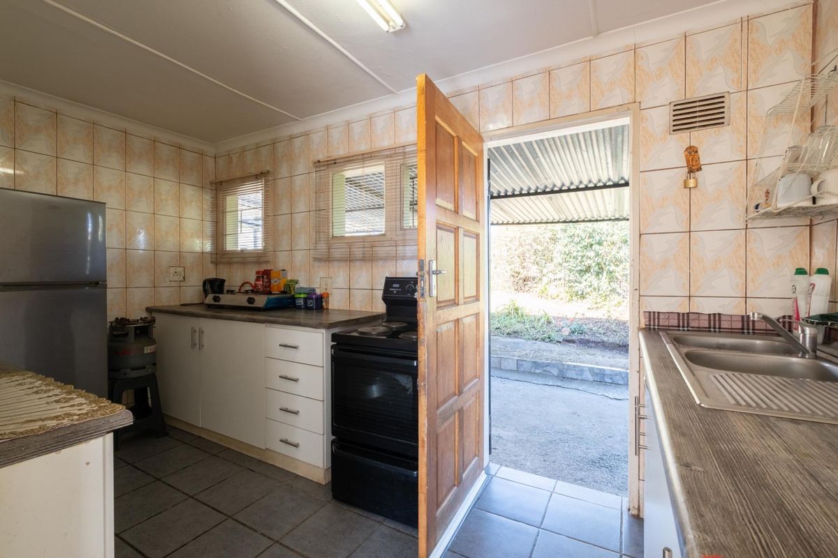 A functional kitchen featuring tiled walls, built-in cabinetry, a double sink, and direct access to an outdoor area.
