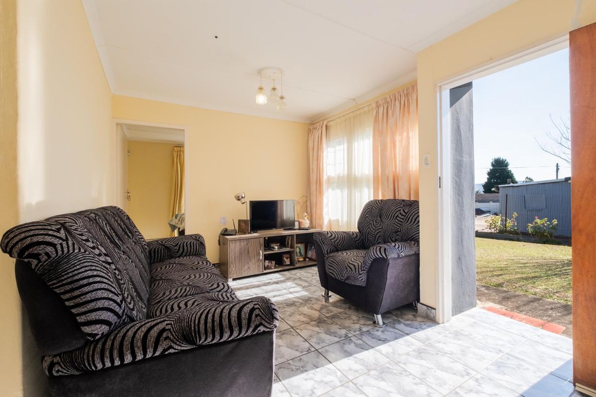 A living room featuring tiled flooring and direct access to the outdoor area through a glass door.
