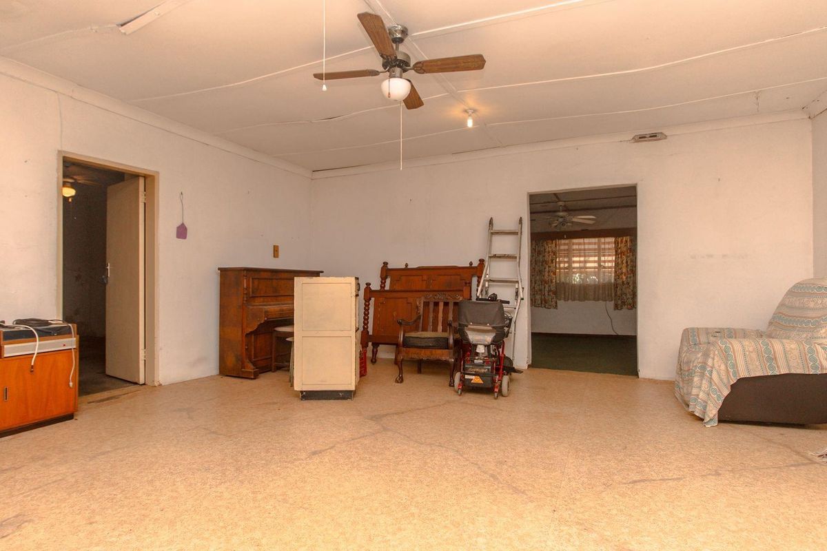 A spacious living area featuring a ceiling fan and neutral finishes, offering a blank canvas for potential renovation and interior design updates.