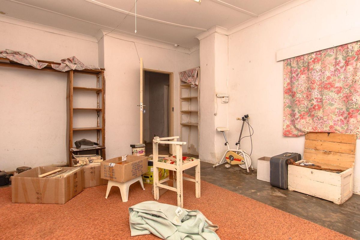 A multi-purpose room featuring worn carpeting, exposed concrete sections, and built-in shelving units, offering a blank canvas for renovation or repurposing.
