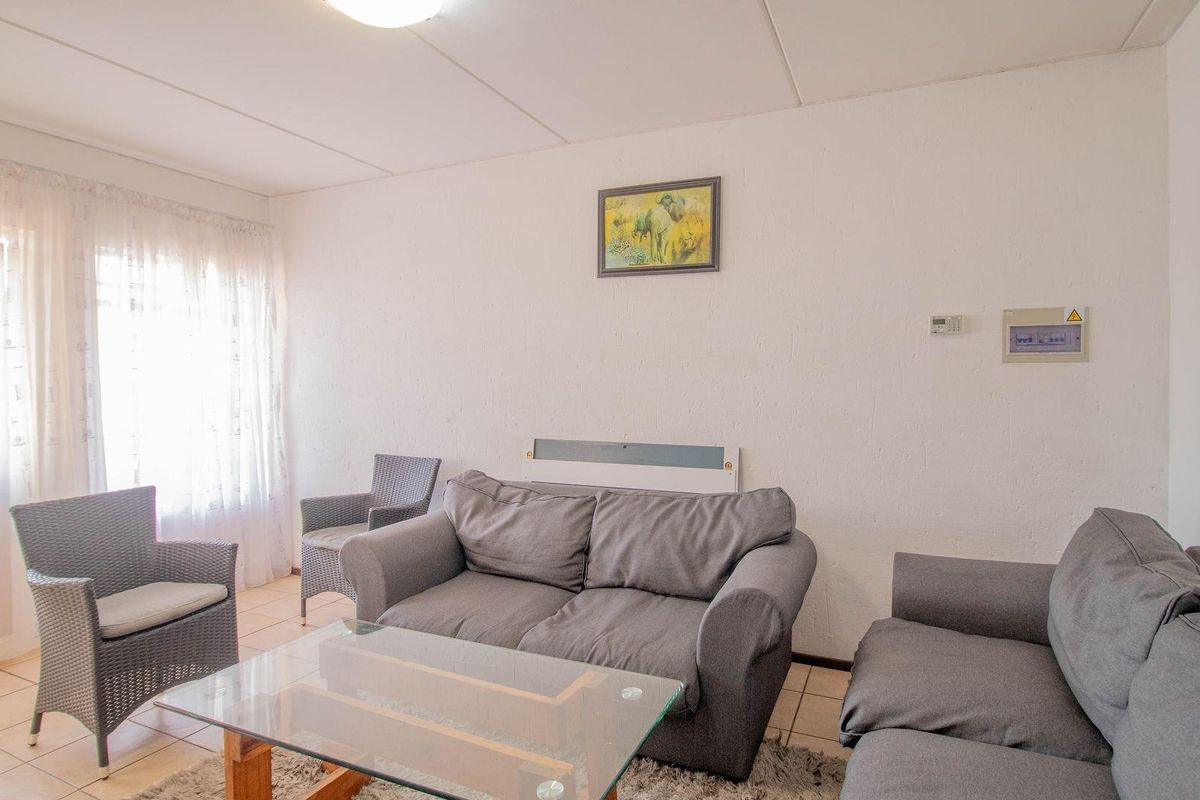 A living room featuring tiled flooring, a wall-mounted heater, and a distribution board, offering a functional space with natural light.