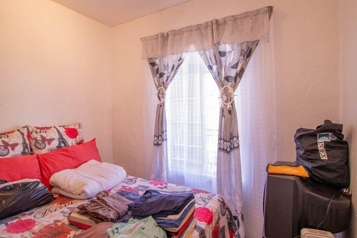 A bedroom featuring a window with installed curtain rods and curtains, providing natural light to the space.