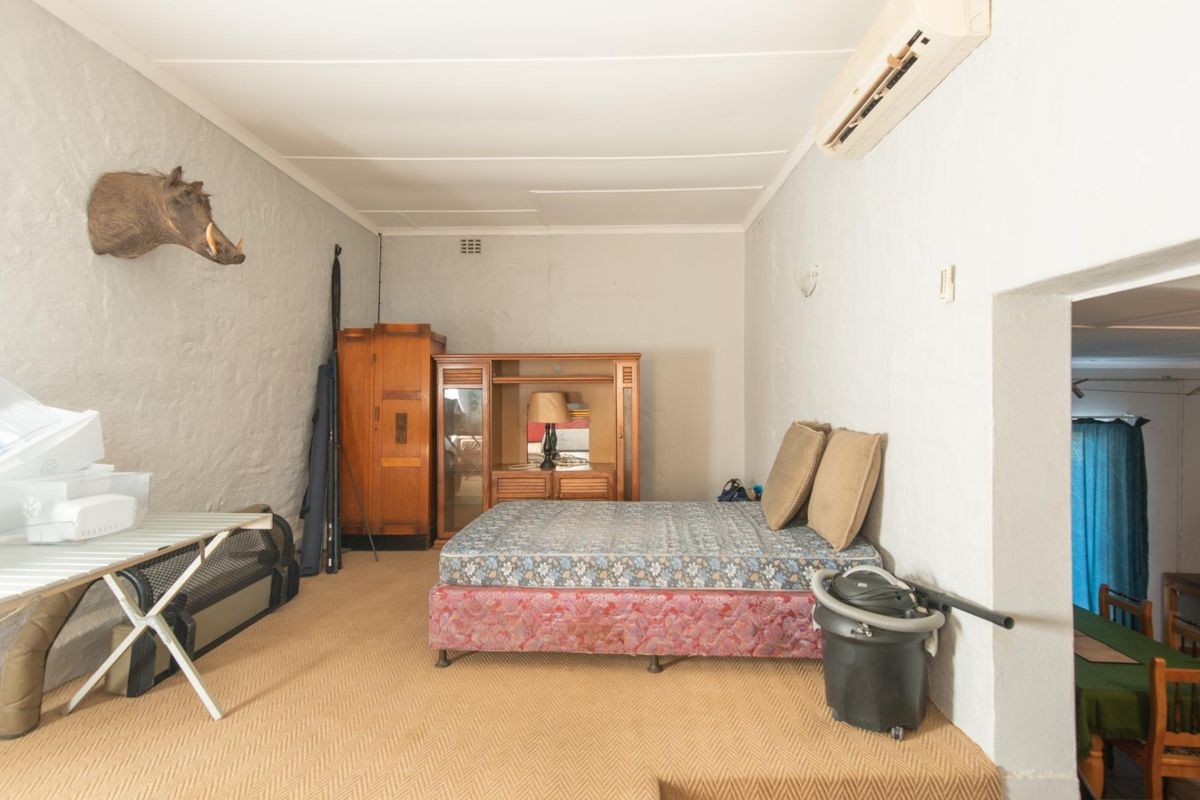 A bedroom featuring a wall-mounted air conditioning unit and textured walls, offering a functional space with potential for modernization.