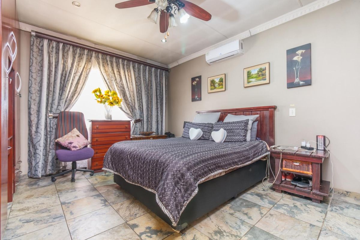 A bedroom featuring tiled flooring, a ceiling fan, and a wall-mounted air conditioning unit.