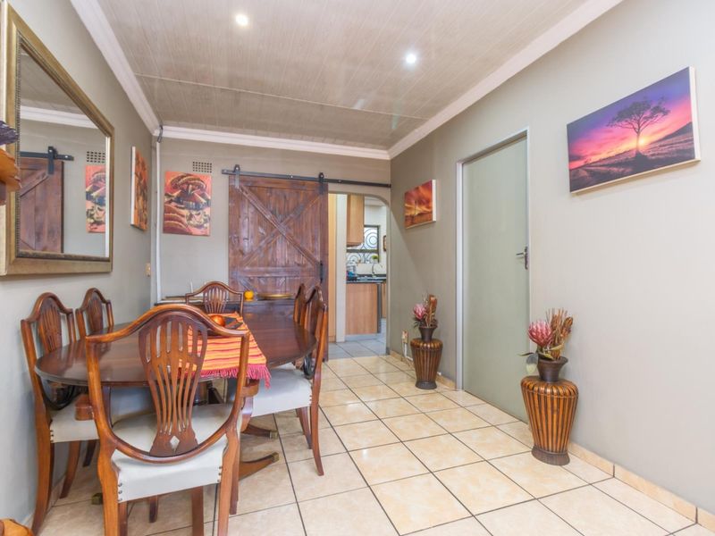 Dining area featuring tiled flooring, a sliding barn-style door, and recessed ceiling lighting, with a view into the adjacent kitchen.