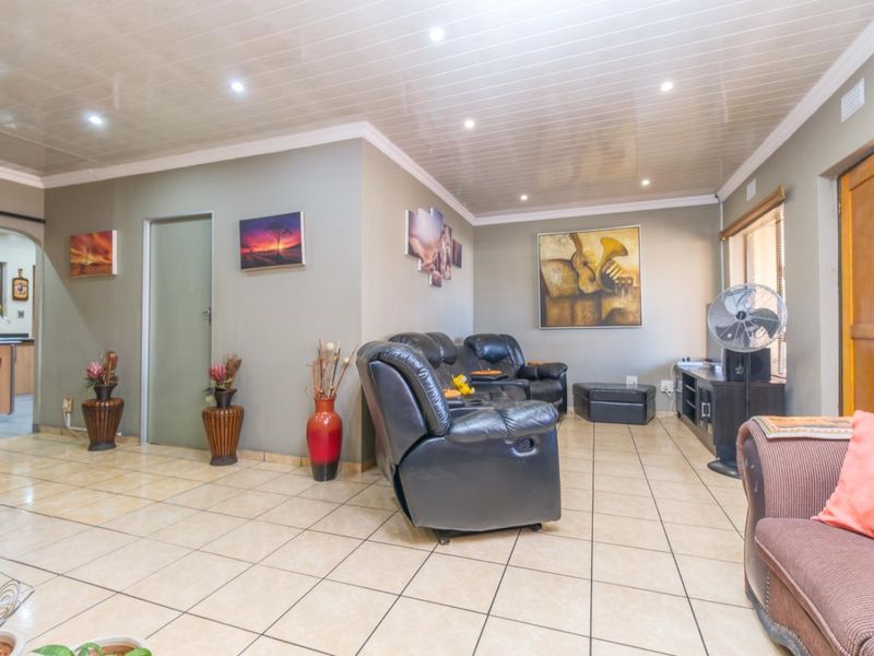 Open plan living area featuring tiled flooring and a glossy panelled ceiling with recessed downlights, providing a functional and connected living space.