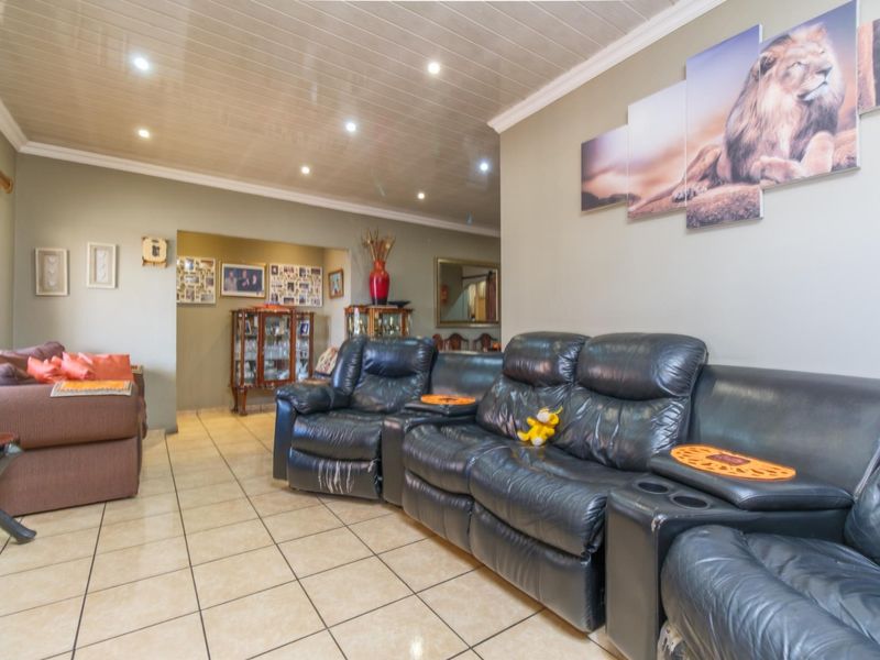 Spacious living room featuring tiled flooring, recessed downlighting, and a glossy panelled ceiling, offering a comfortable and functional family living space.