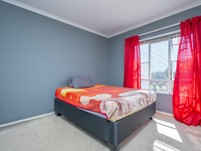 A bedroom featuring grey painted walls, carpeted flooring, and a large window with natural light.