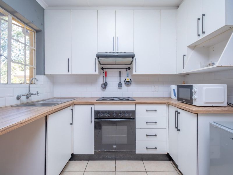 A functional kitchen featuring white cabinetry, wood-look laminate countertops, a built-in oven with extractor fan, and a stainless steel sink.