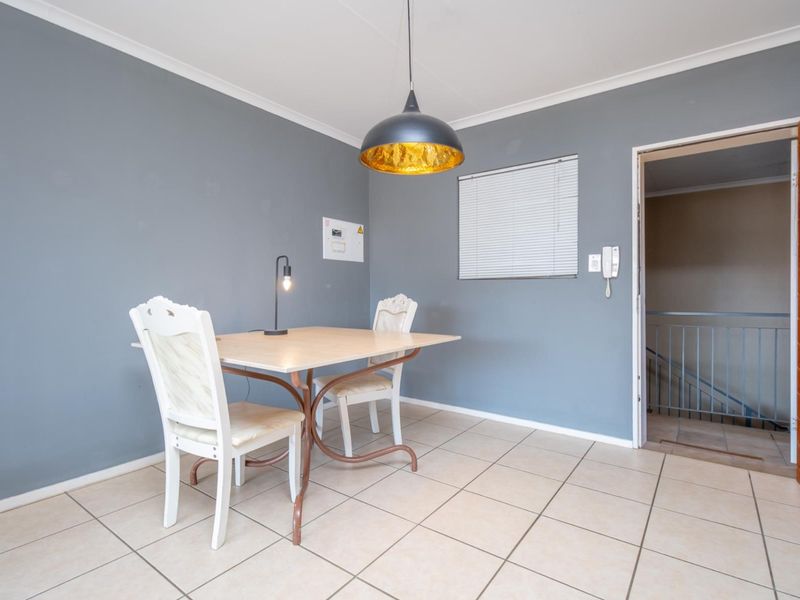 A dining area featuring tiled flooring, a pendant light fixture, and an intercom system, with direct access to the building hallway.