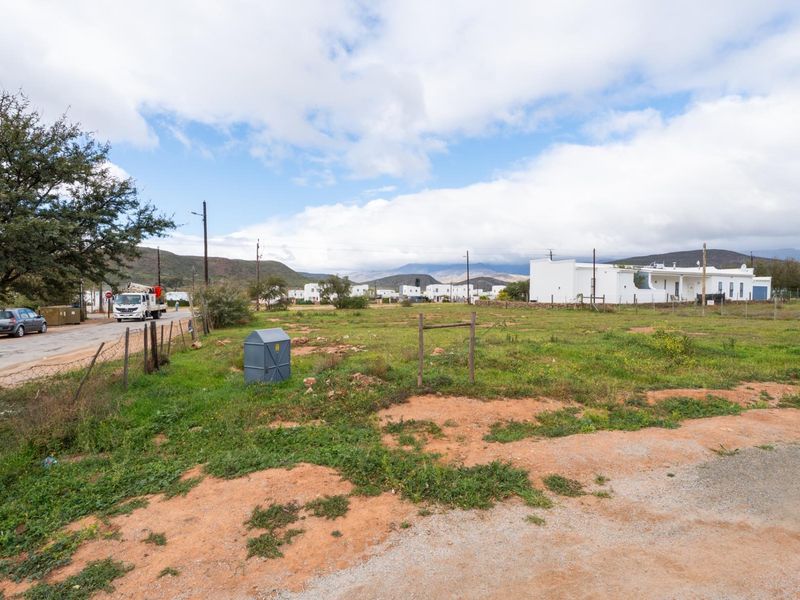 A vacant residential plot of land featuring natural vegetation, perimeter fencing, and access to local street infrastructure.