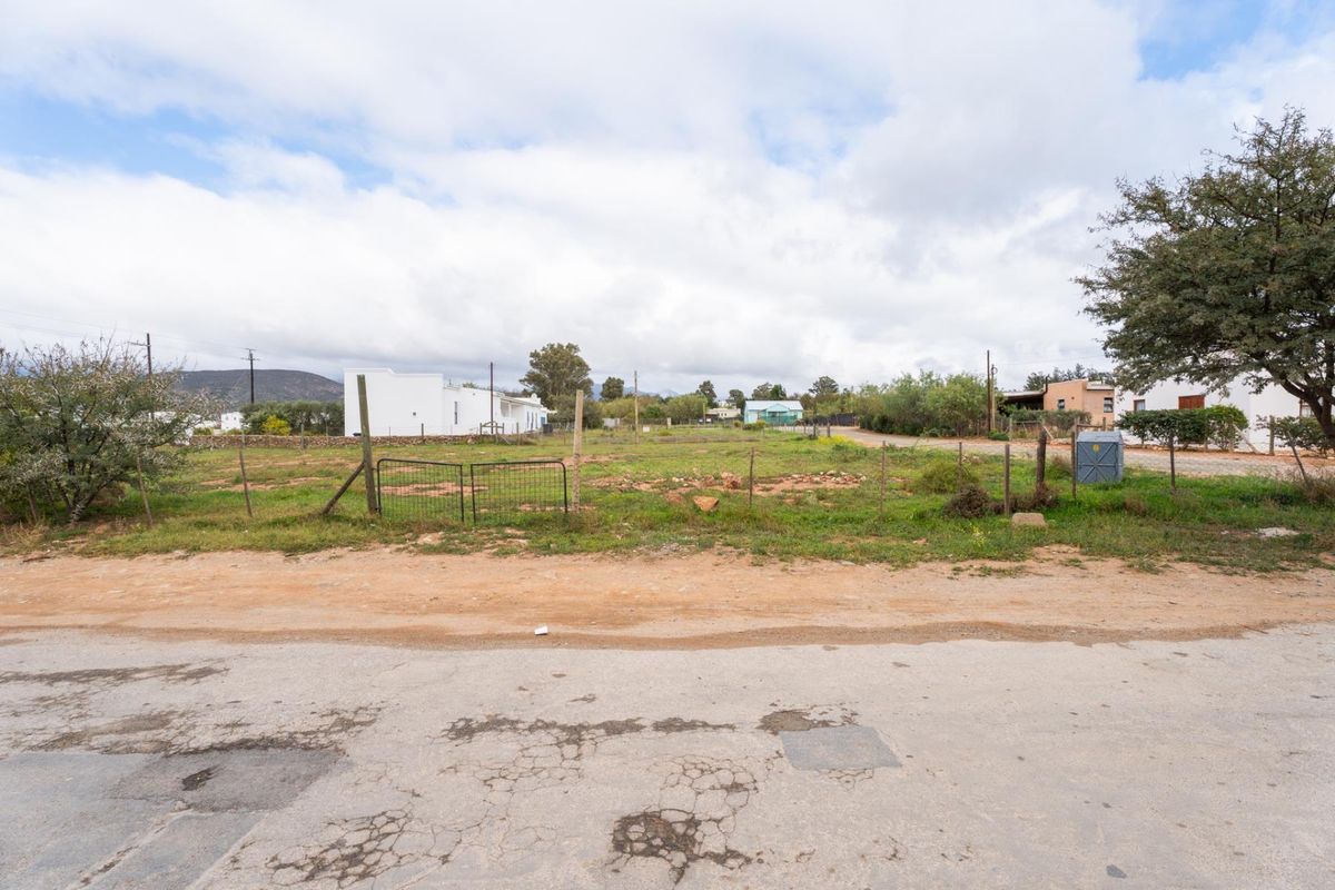 A vacant residential plot of land featuring wire fencing, accessible from an unpaved road, offering a clear space for potential development.