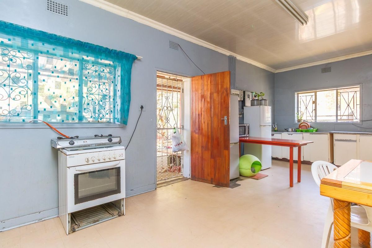 A functional kitchen space featuring a freestanding stove, basic cabinetry, and direct access to an outdoor area.