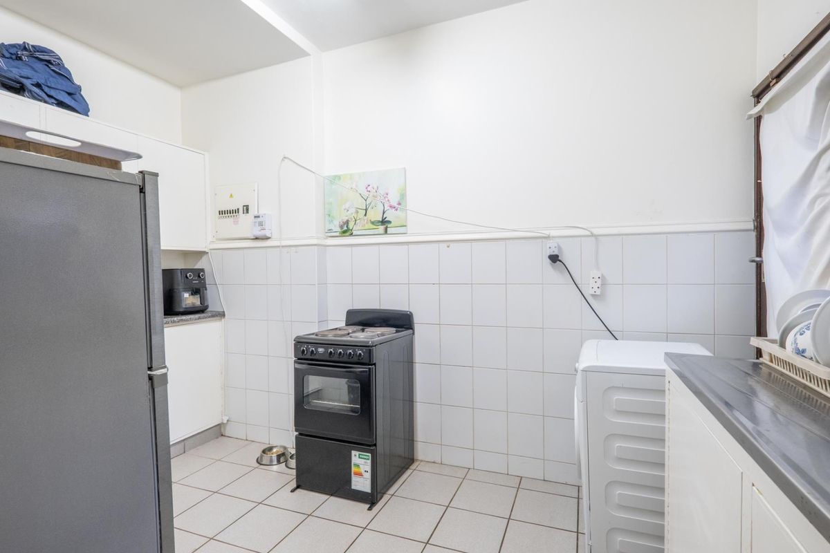 Functional kitchen area featuring tiled walls, built-in cabinetry, and space for a freestanding stove and laundry appliances.