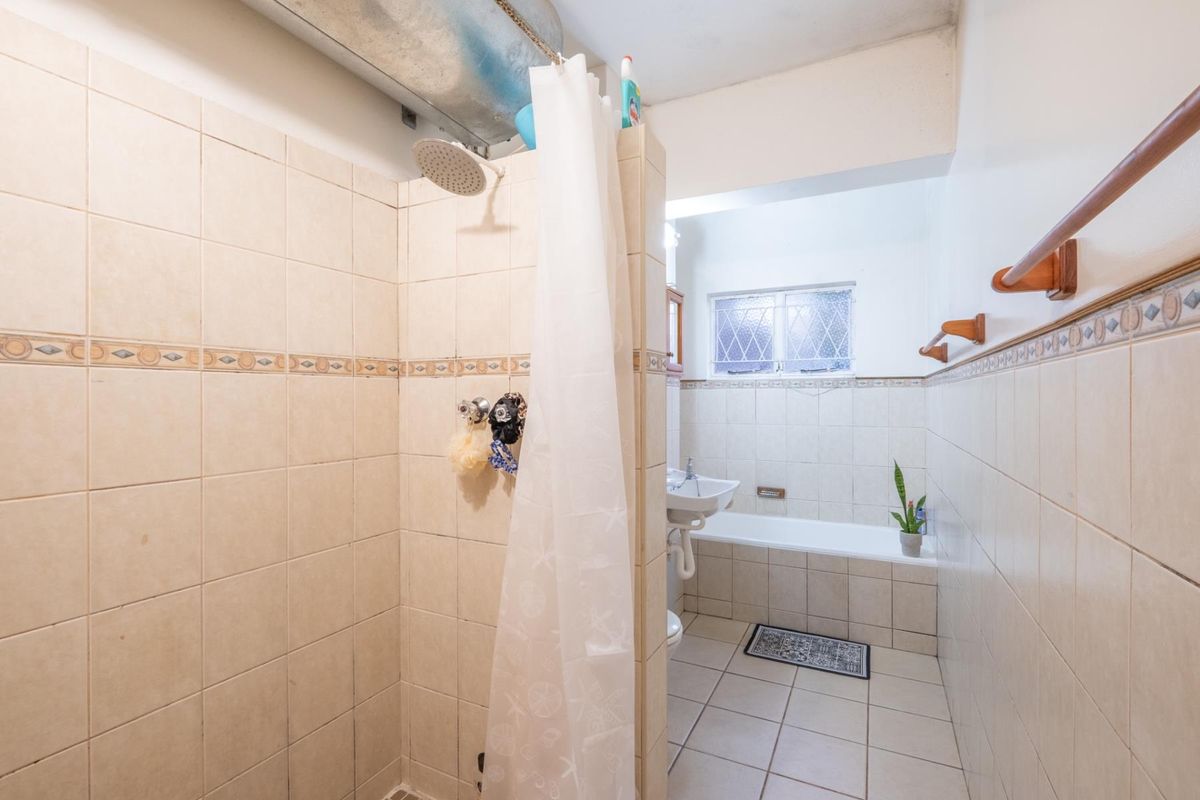 A dated bathroom featuring a tiled shower enclosure, a separate bathtub, and a pedestal sink with exposed overhead ductwork.