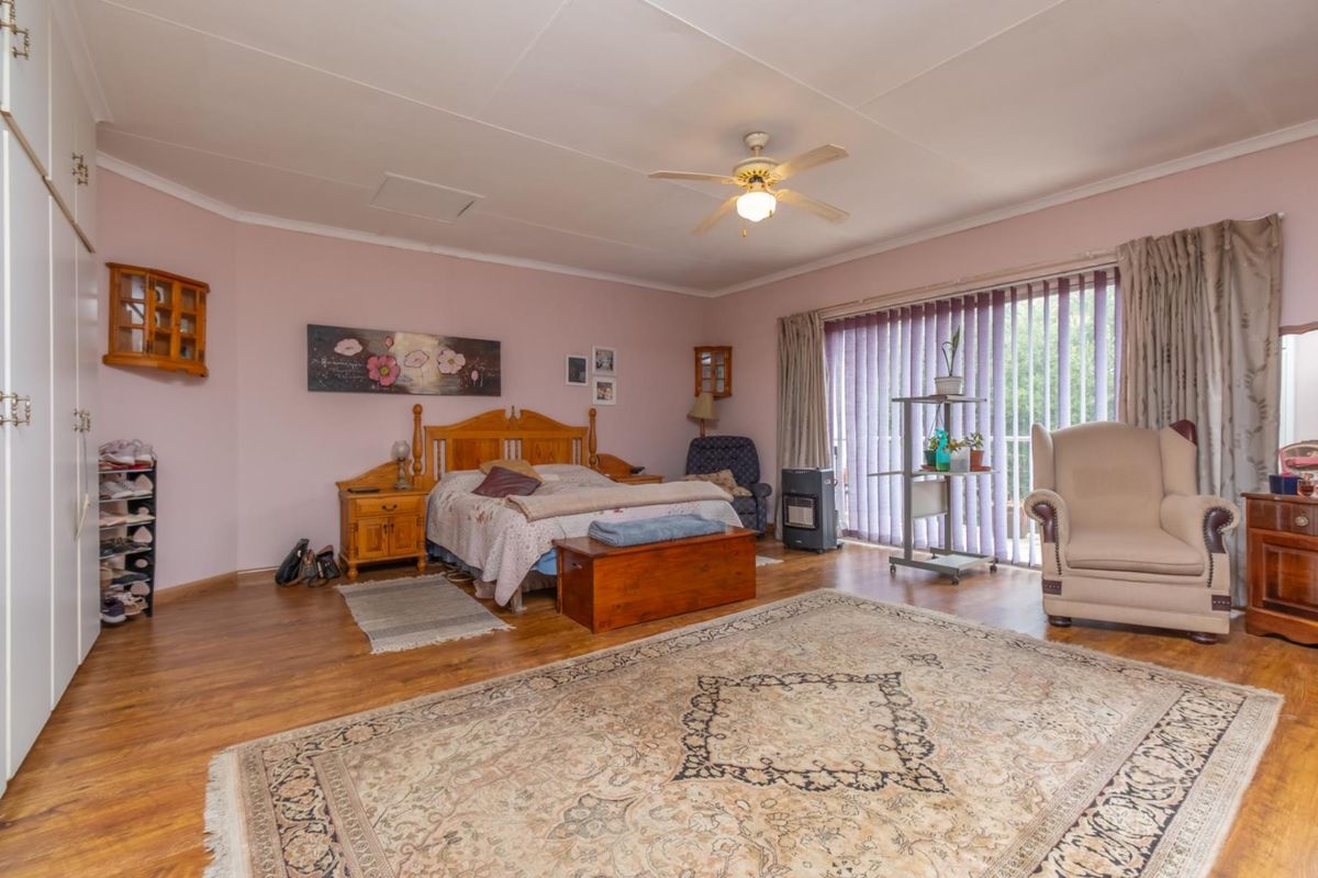 Spacious bedroom featuring built-in cupboards, laminate flooring, a ceiling fan, and large sliding doors providing access to the exterior.