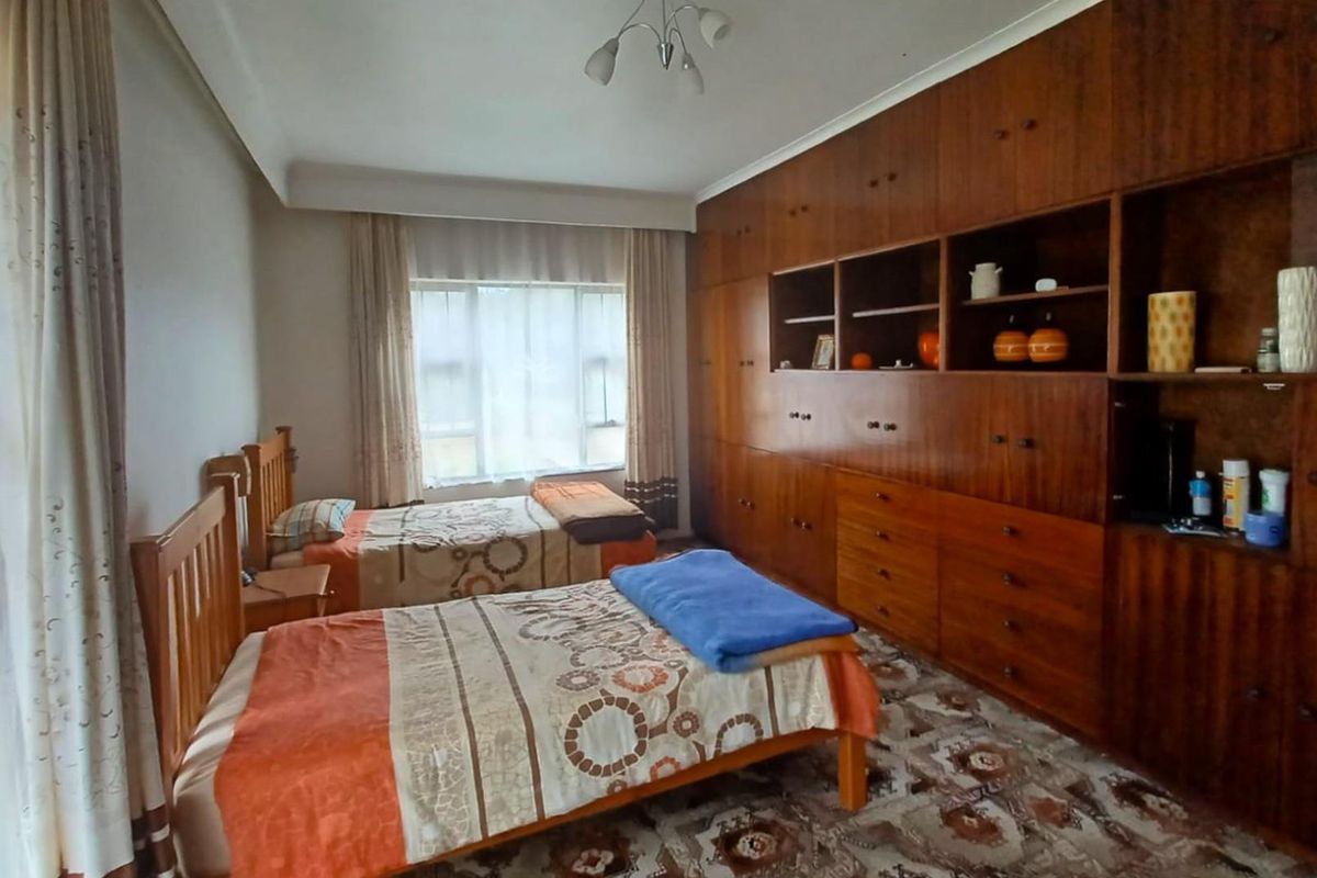 Spacious bedroom featuring extensive floor-to-ceiling built-in wooden cabinetry and large windows allowing for natural light.