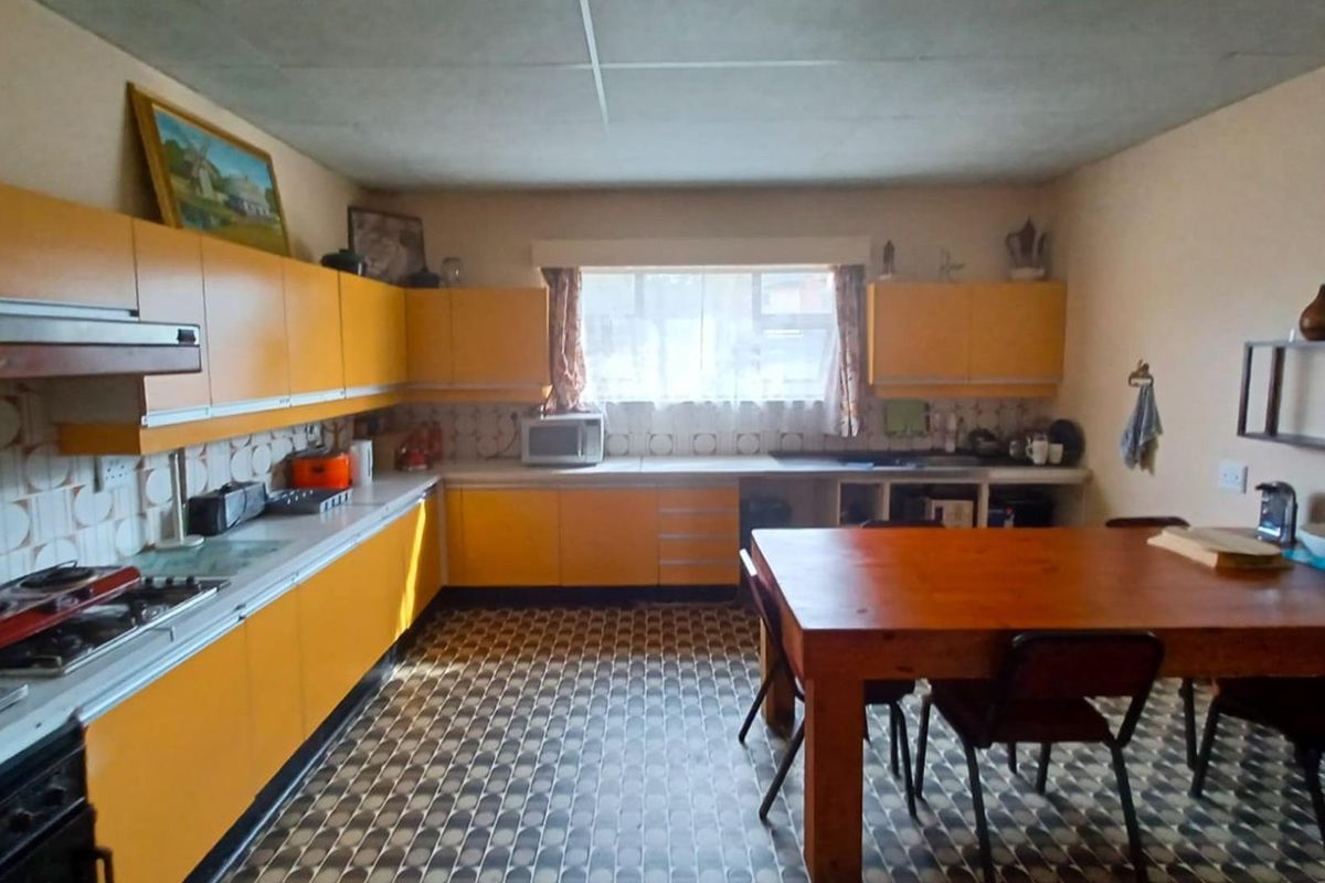 A spacious, retro-style kitchen featuring bright yellow cabinetry, patterned flooring, and a built-in hob and extractor fan.