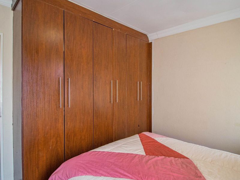 A bedroom featuring built-in wooden cabinetry with modern handles and crown molding.