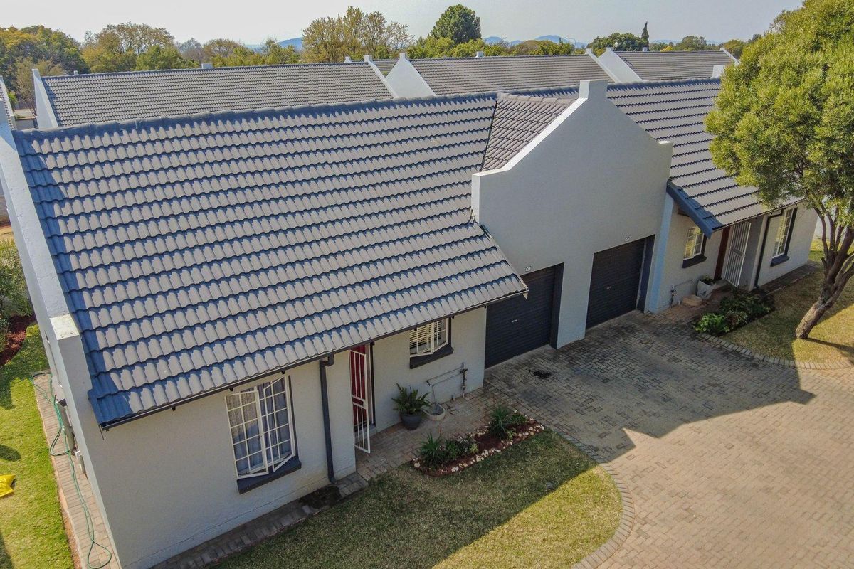 Aerial view of a townhouse complex featuring tiled roofs, paved driveways, and well-maintained exterior facades with integrated garage doors.