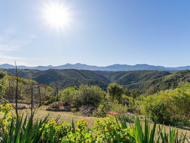 A scenic, elevated view overlooking lush green hills and distant mountain ranges, showcasing the natural landscape of the farm property.