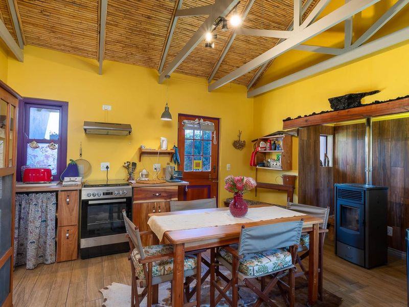 Open-plan kitchen and dining area featuring a vaulted bamboo ceiling, wood-look flooring, a built-in stove, and a freestanding fireplace.