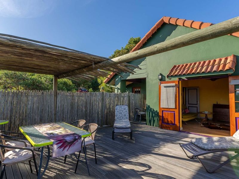 A rustic outdoor timber deck featuring a natural wood pergola, providing a shaded transition space between the garden and the main dwelling.