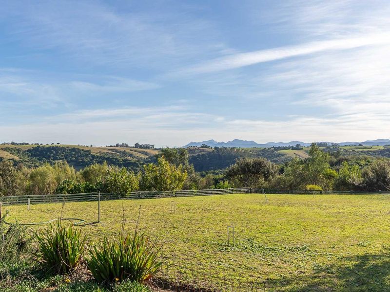 Expansive rural landscape view featuring rolling hills and distant mountains, showcasing the natural beauty and open space of the farm property.