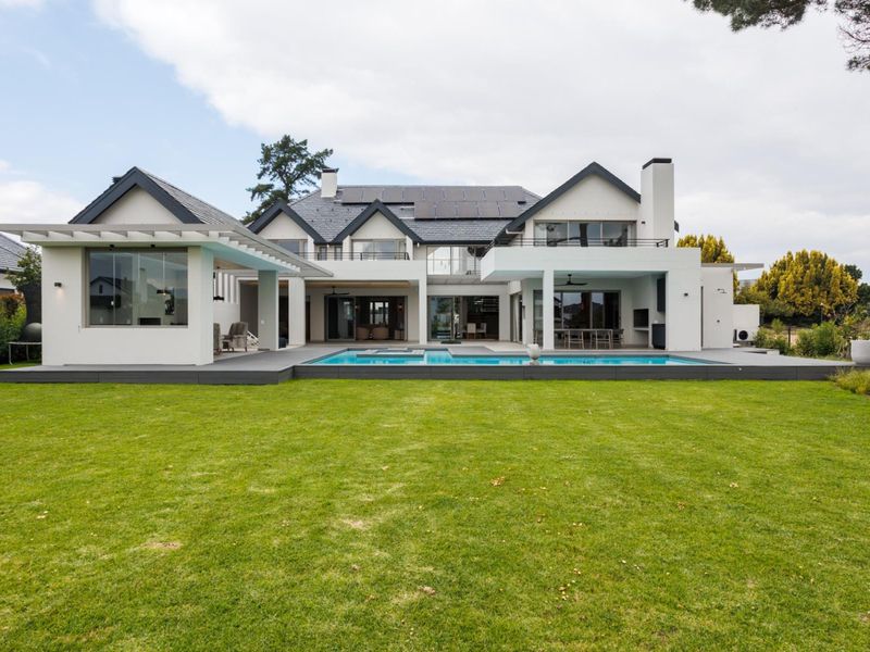 A spacious rear exterior view featuring a modern multi-level home, a swimming pool, a covered patio area, and a well-maintained lawn.