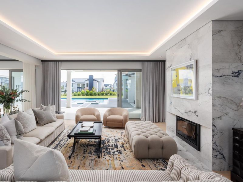 Spacious living room featuring a floor-to-ceiling marble fireplace, recessed ceiling lighting, and large sliding glass doors opening to a patio and pool area.