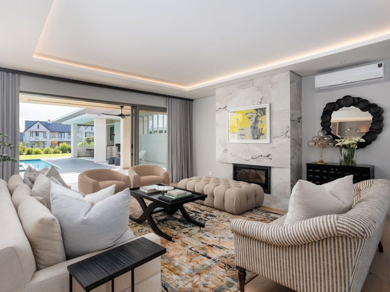 Modern living room featuring a marble-clad fireplace, recessed ceiling lighting, split-system air conditioning, and large sliding glass doors opening to a patio and pool area.