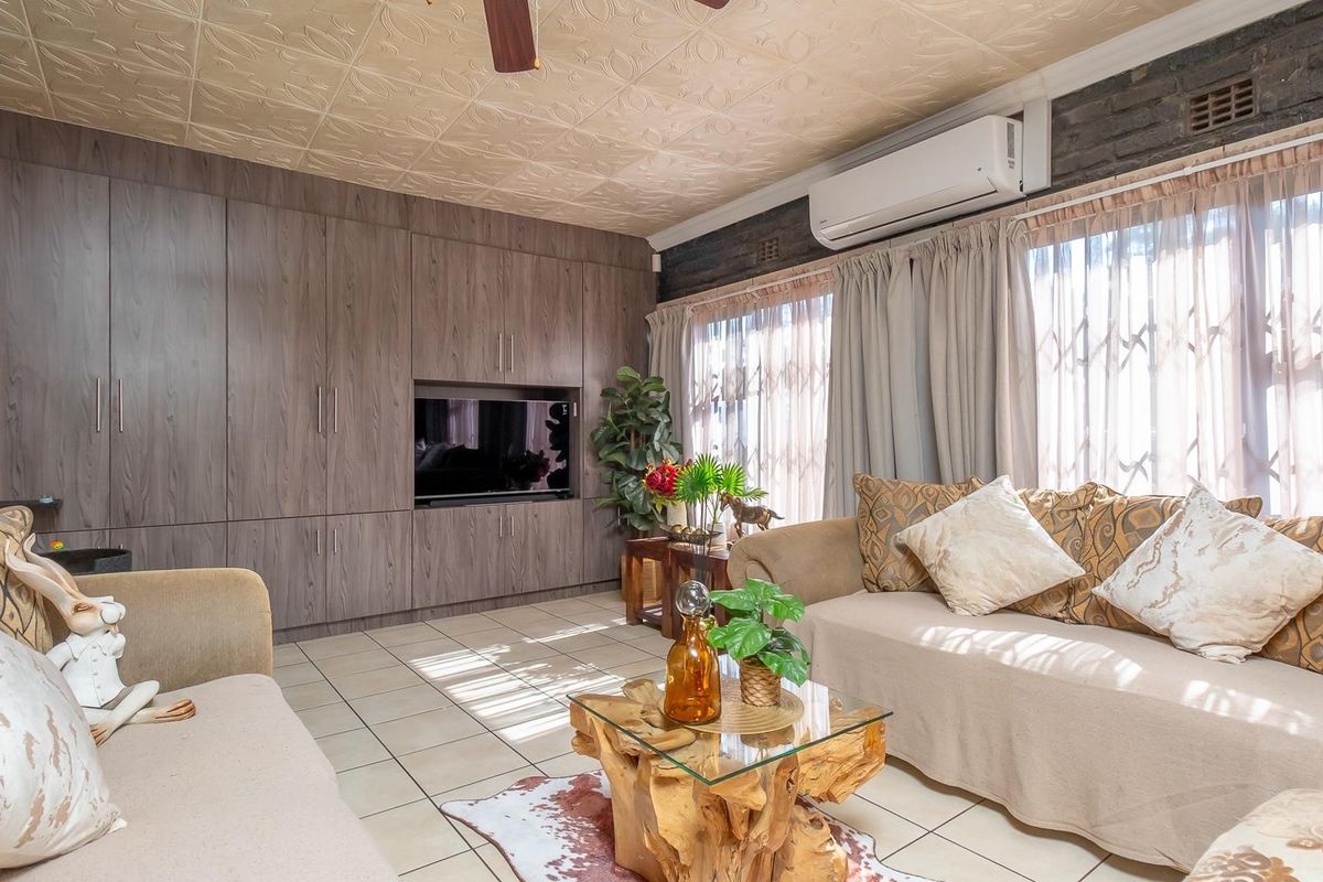 A living room featuring built-in wooden cabinetry, tiled flooring, a textured ceiling, and a wall-mounted air conditioning unit.