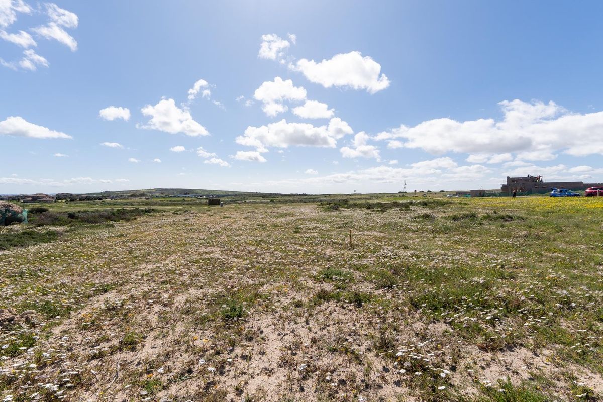 A wide-angle view of a vacant residential plot featuring natural vegetation and open landscape, offering potential for future development.