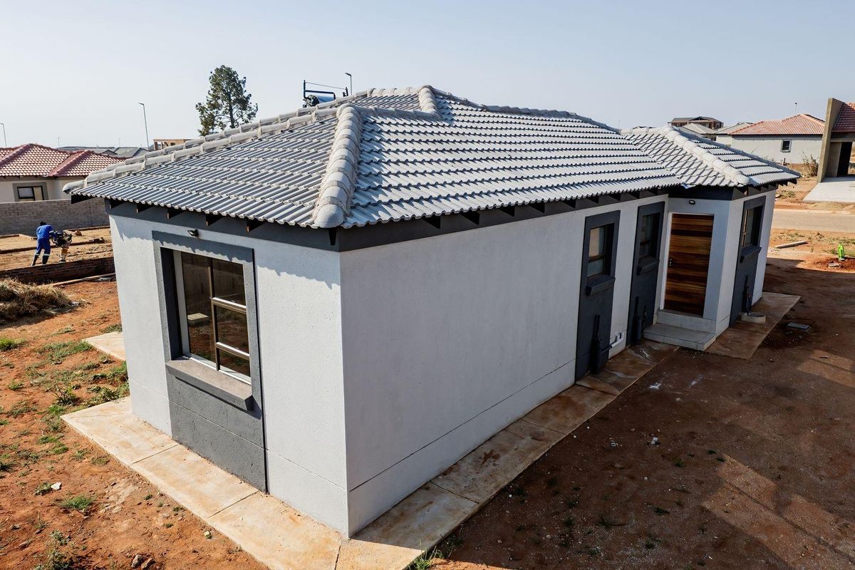 A newly constructed single-story residential house featuring a tiled hip roof, modern exterior finishes, and a concrete perimeter walkway.