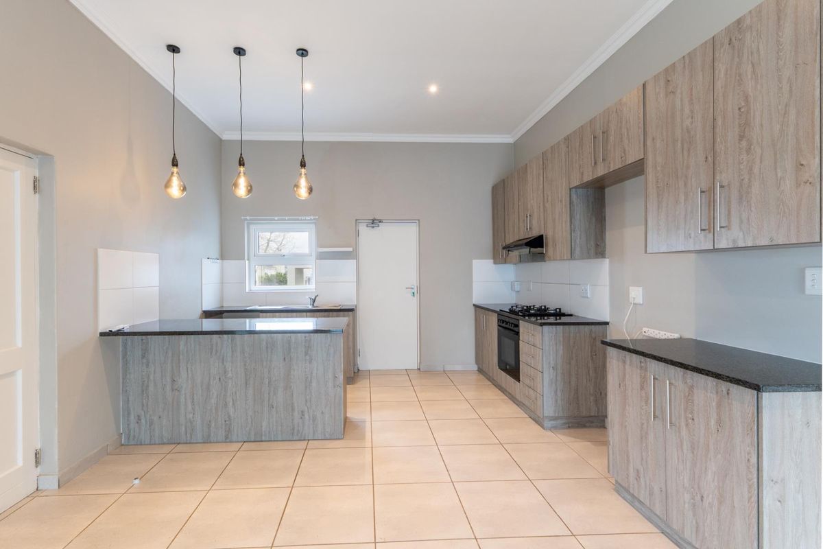 Modern kitchen featuring wood-look cabinetry, granite countertops, gas hob, built-in oven, and tiled flooring in an open-plan layout.