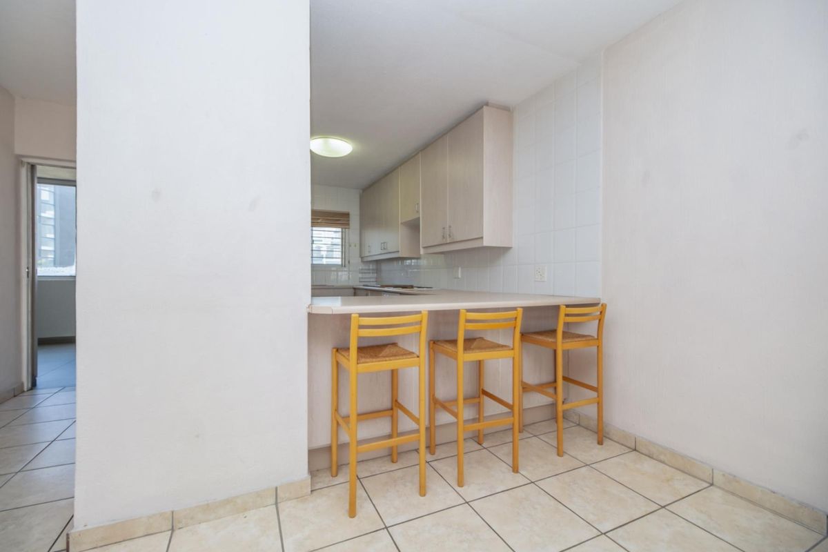 A functional kitchen featuring a breakfast bar, light-toned cabinetry, and tiled flooring, providing a practical layout for daily meal preparation.