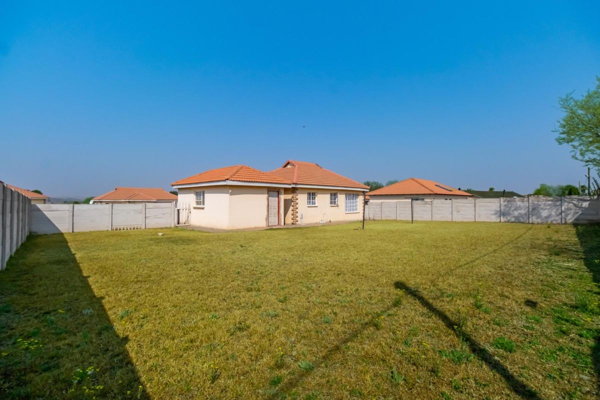 A view of the rear exterior of the house, featuring a spacious backyard enclosed by precast concrete walling and a tiled roof structure.