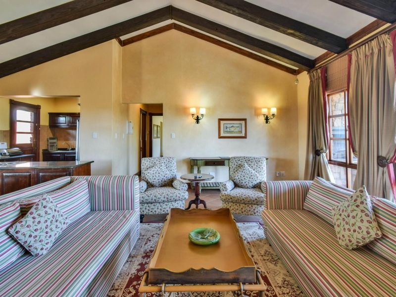 Spacious open-plan living area featuring a vaulted ceiling with exposed timber beams, warm wall finishes, and an integrated kitchen space.