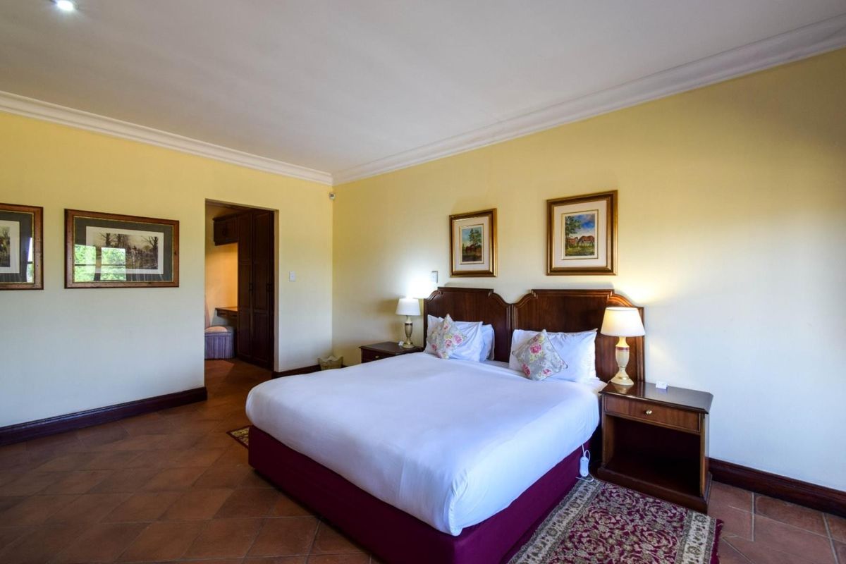 Spacious bedroom featuring tiled flooring, cove cornicing, and an adjoining dressing area with built-in cabinetry.