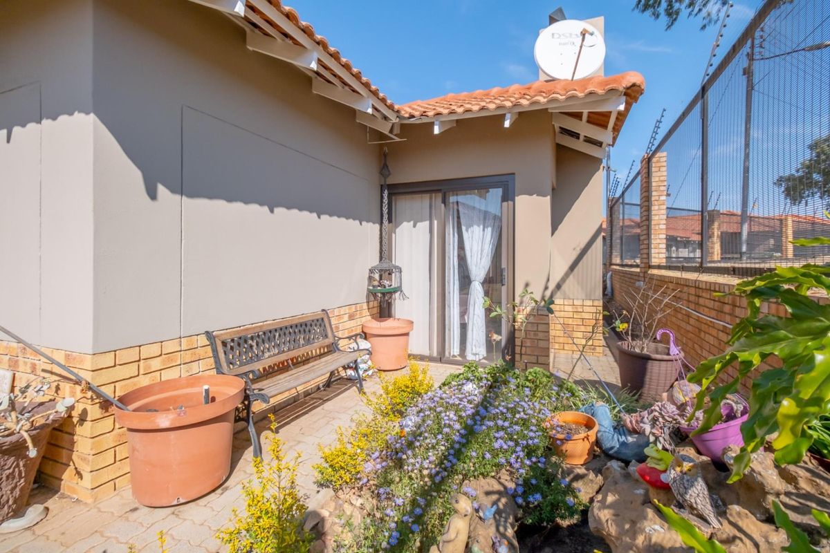 A private rear patio area featuring paved flooring, brick wall accents, and direct access to the interior through sliding glass doors.
