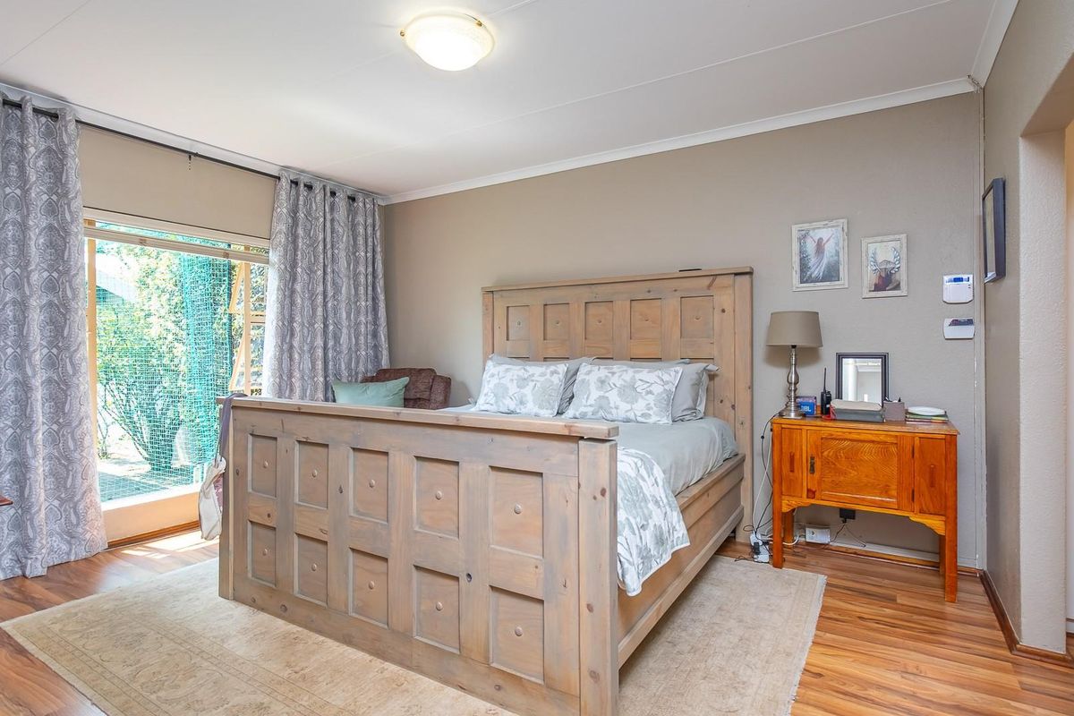 A well-maintained bedroom featuring wood-look laminate flooring, a ceiling-mounted light fixture, and a sliding glass door providing access to the exterior.