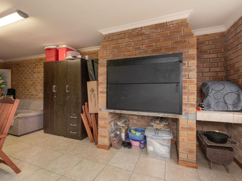 Covered patio area featuring an exposed brick wall and a built-in braai, providing a functional space for outdoor entertainment and dining.