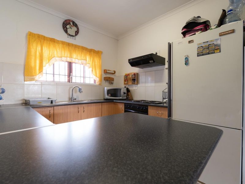 A functional kitchen featuring laminate cabinetry, dark countertops, a tiled backsplash, and built-in cooking appliances, offering a practical layout for daily meal preparation.