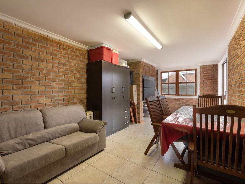 A living area featuring exposed brick walls, ceramic tiled flooring, and a built-in fireplace, offering a rustic aesthetic with potential for modern updates.