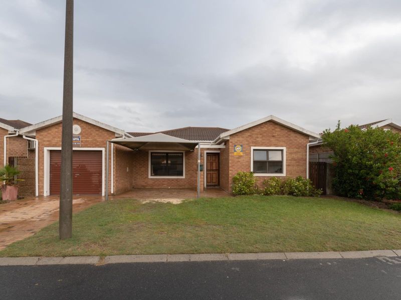 Front elevation of a brick townhouse featuring a single garage, a shade sail carport, and a small front garden area.
